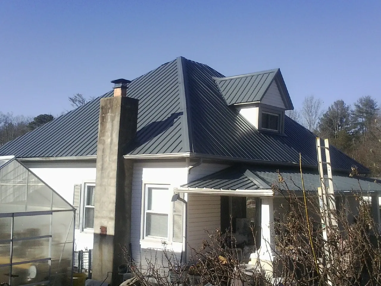 Dark blue standing seam metal roof on a white farmhouse with dormer — Slate & Tile Roof Repair by Roofing Brothers in Scottsboro