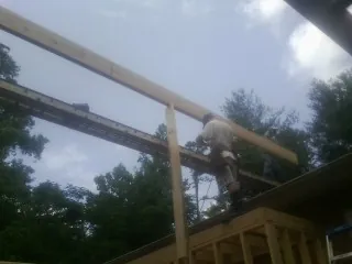 Carpenter setting a ridge beam over a new addition frame — Ice Dam Removal by Roofing Brothers in Scottsboro