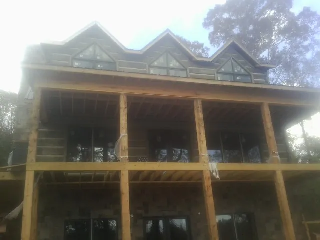 Dormers and porch framing on a large log home under construction — Roof Coating work by our crew in Scottsboro