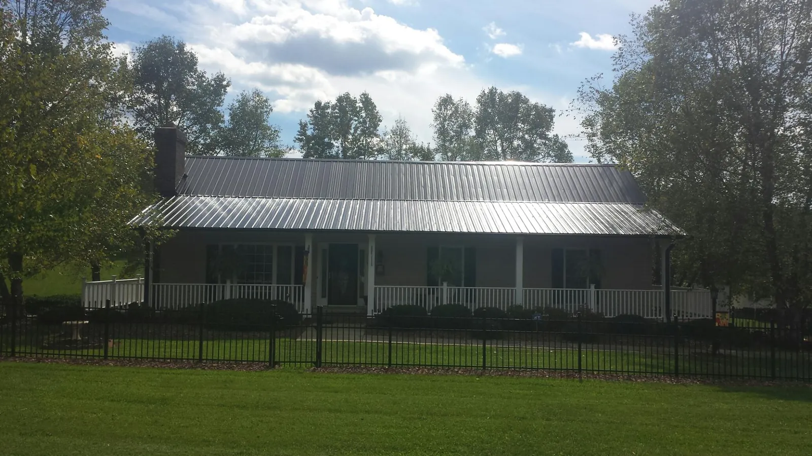 Gray metal roof on a brick ranch with a full width front porch — Gutter Guard Installation work by our crew in Scottsboro