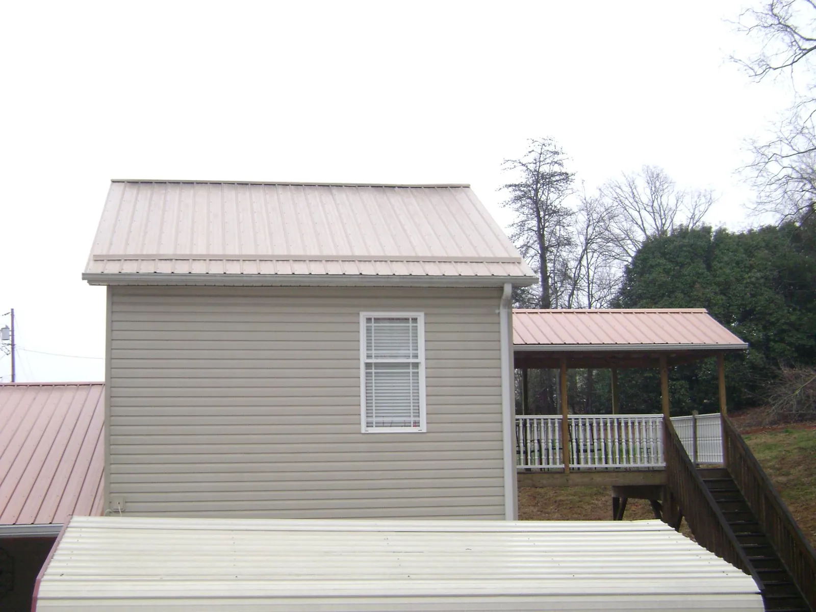 Tan metal roofs on a two story addition and attached porch, from a Roof Replacement job in Scottsboro