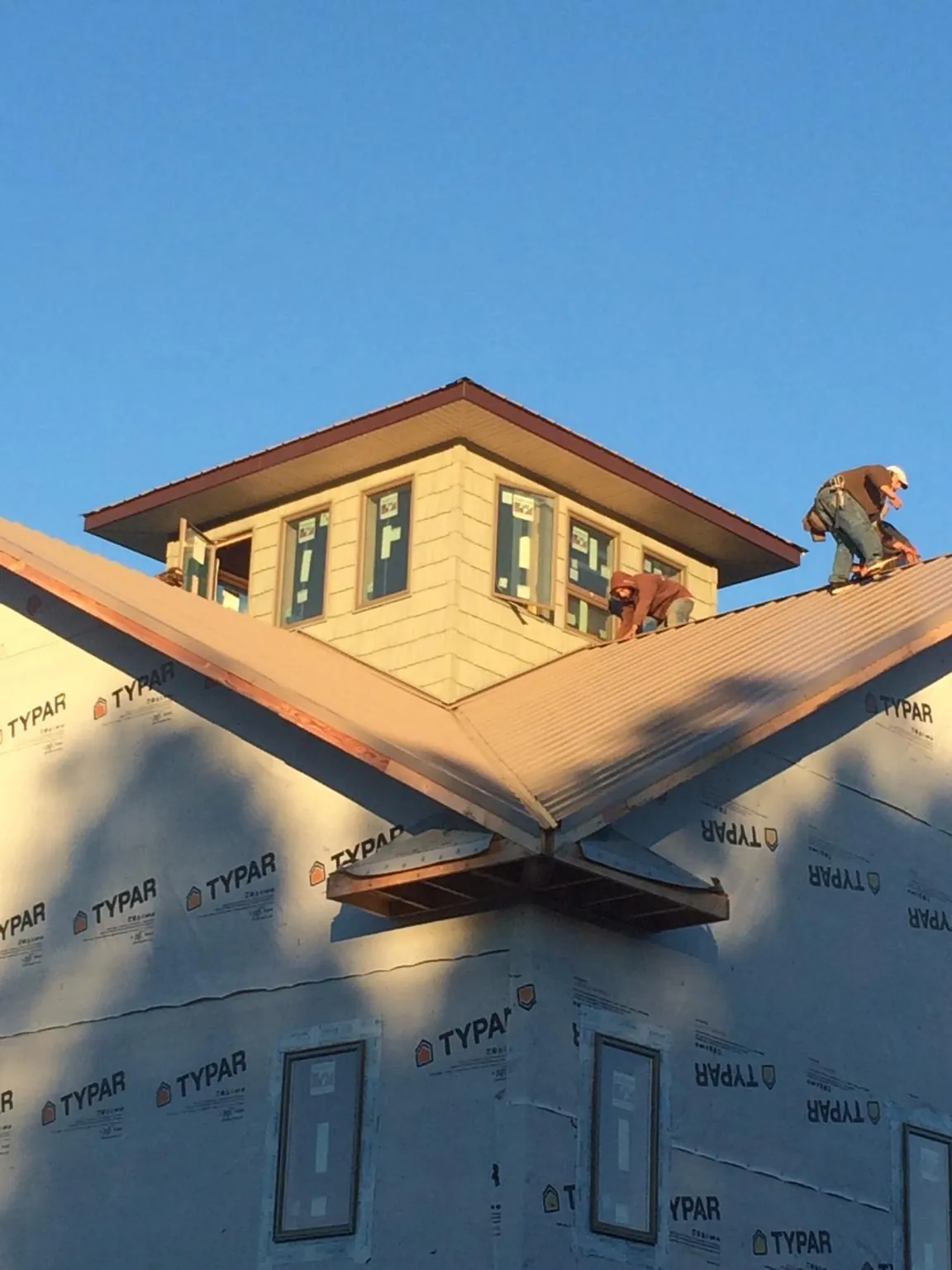 Roofers working around a rooftop cupola on a new metal roof at sunset — Roof Waterproofing in Scottsboro by Roofing Brothers